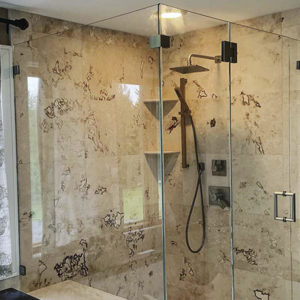 Glass enclosure surrounding tiled shower with built-in seating and shelving